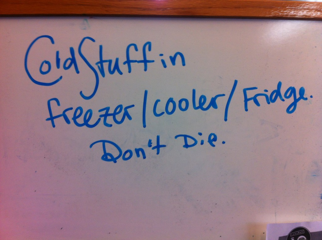 Whiteboard with the words 'cold stuff in freezer/cooler/fridge. Don't die.'