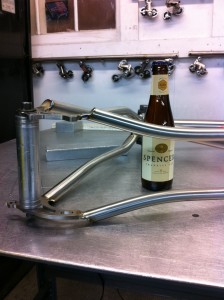 An unopened craft beer on the weld bench where a freshly welded Seven cools