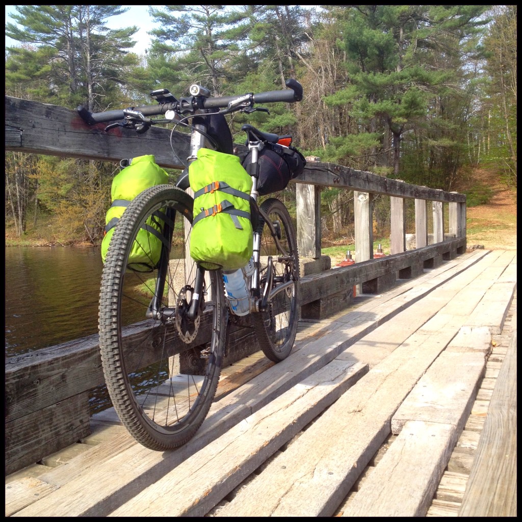 Seven with handlebar bags parked on a wooden bridge