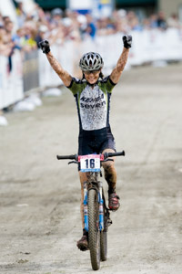 Mary McConneloug crossing the finish line with arms up in victory