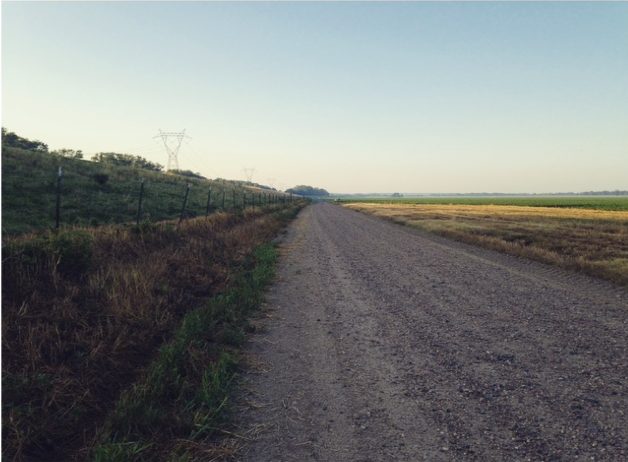 A long dirt road on an enrmous field