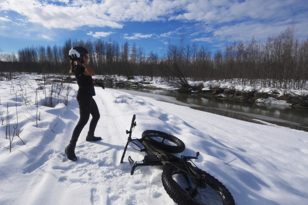 woman takes a break from winter bikepacking to throw a snowball