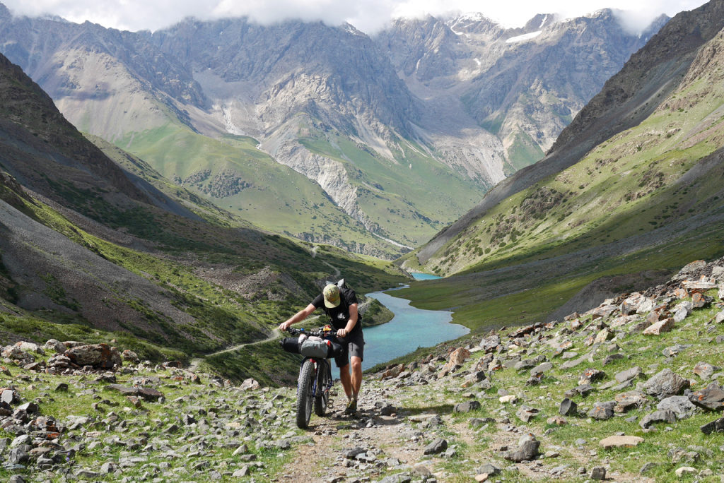 A cyclist pushes his bike up a steep mountain road in Kyrgyzstan