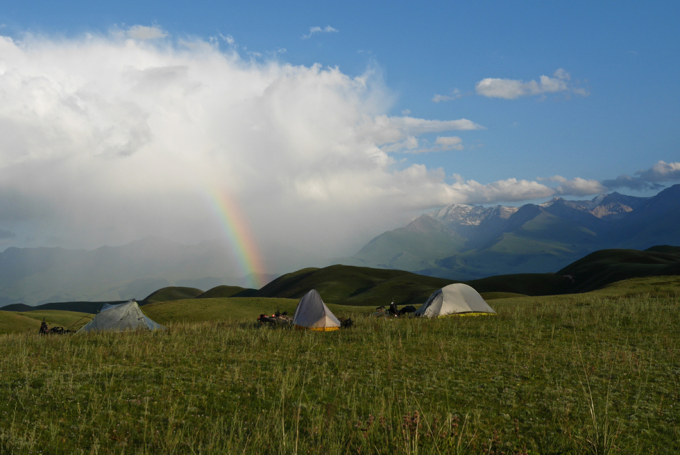 a rianbow touches down behind a remote campsirte in the foothills of Kyrgyzstan