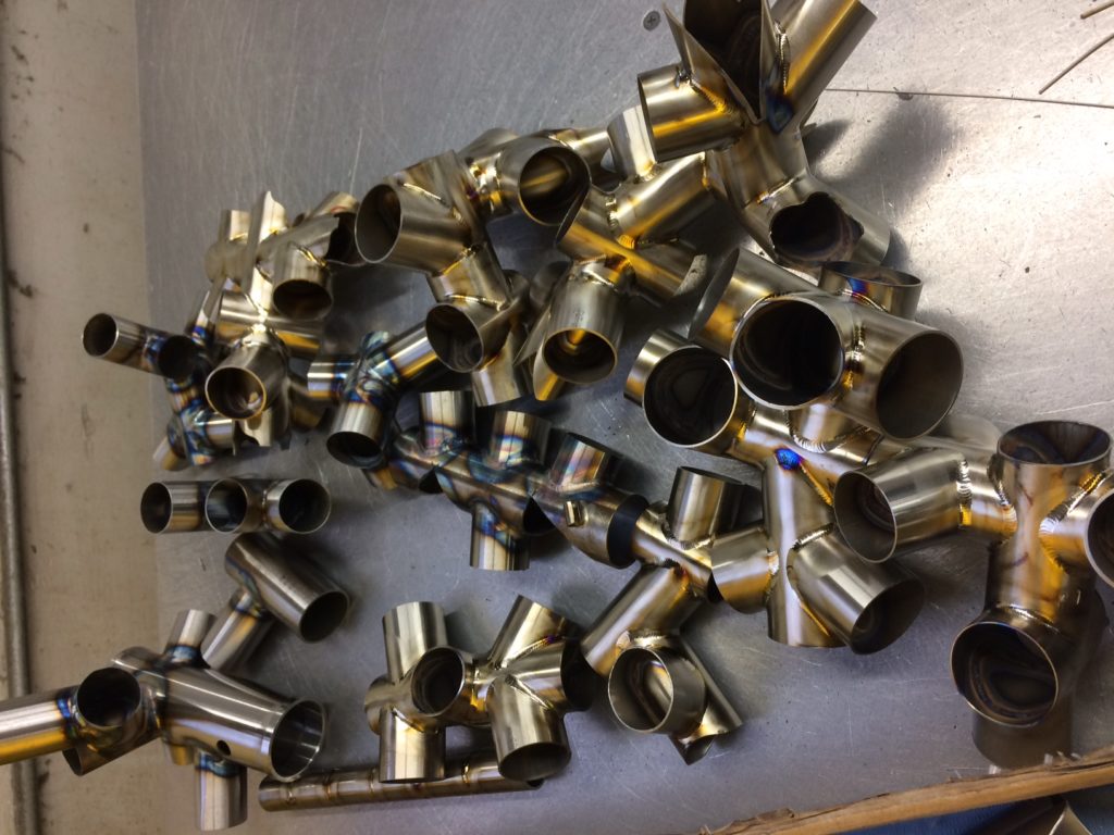 Dozens of short coped pieces TIG welded together on a work bench