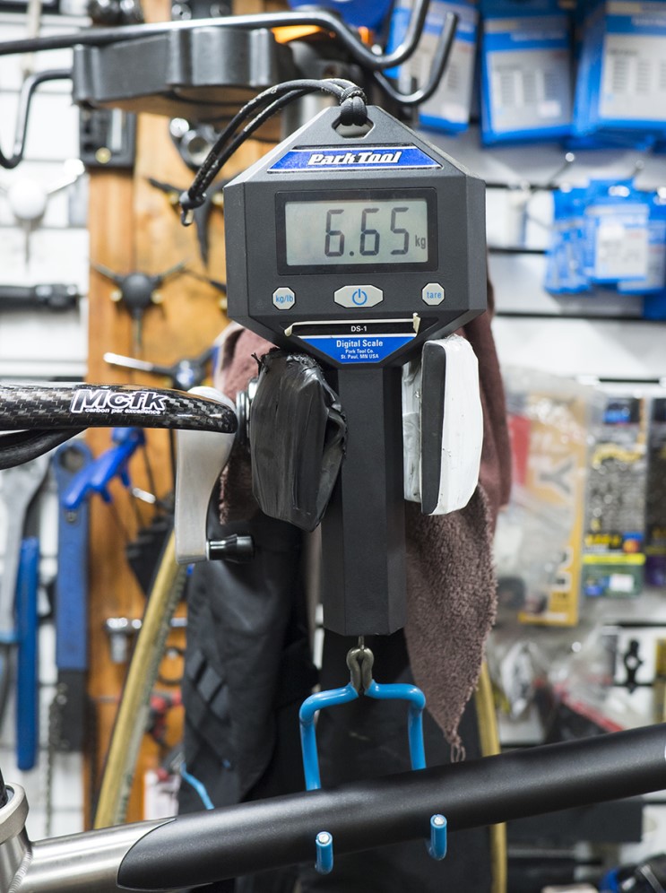 A scale that reads 6.66 kg holds a Seven ti/carbon bicycle