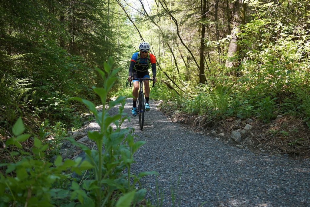 Jeremy rides toward the camera on a gravel trail