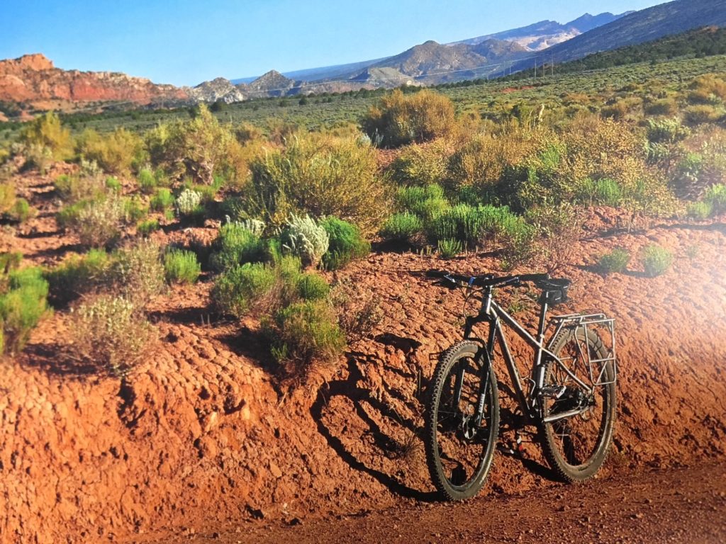 A Seven mountain bike leans against a desert dirt ridge