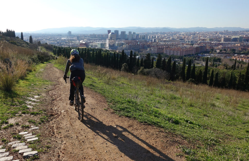 a cyclist casts a long early morning shadow as she approaces the edge of Barcelona