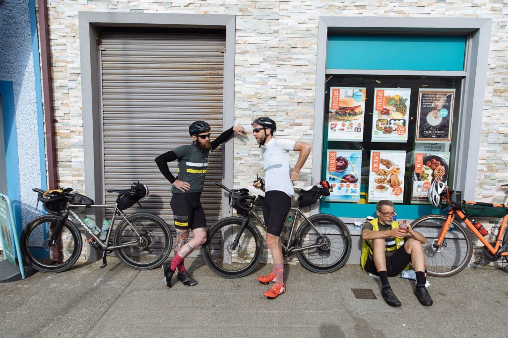 three cyclists take a rest at a storefront