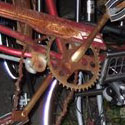 the original MoKeefe commuter bike with a rusty cruiser bicycle frame across its built in open front rack.