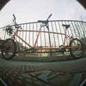 a fisheye photo of an orange tandem bicycle with 20-inch wheels